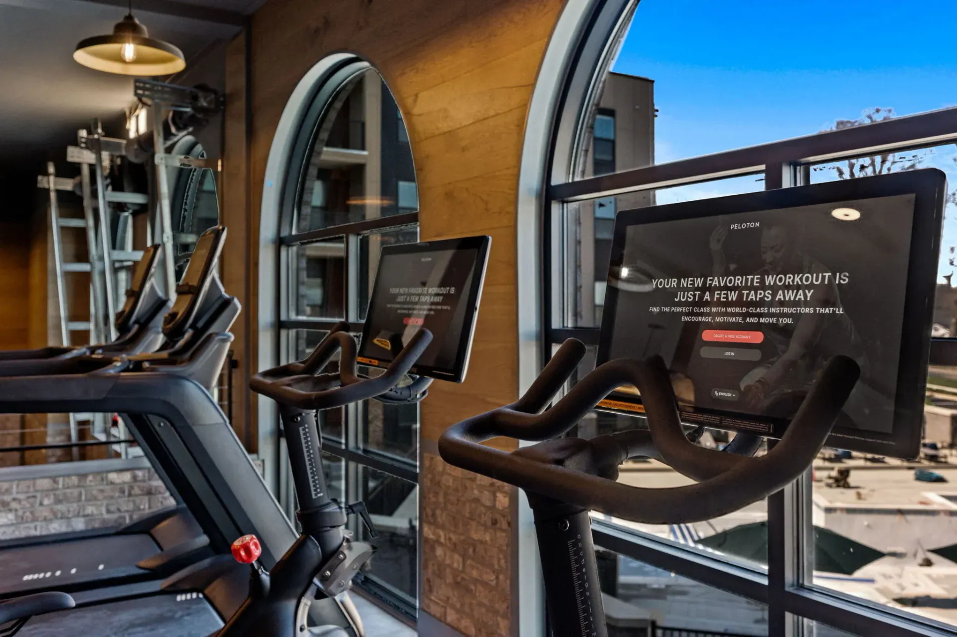 Indoor gym with treadmills and large windows.