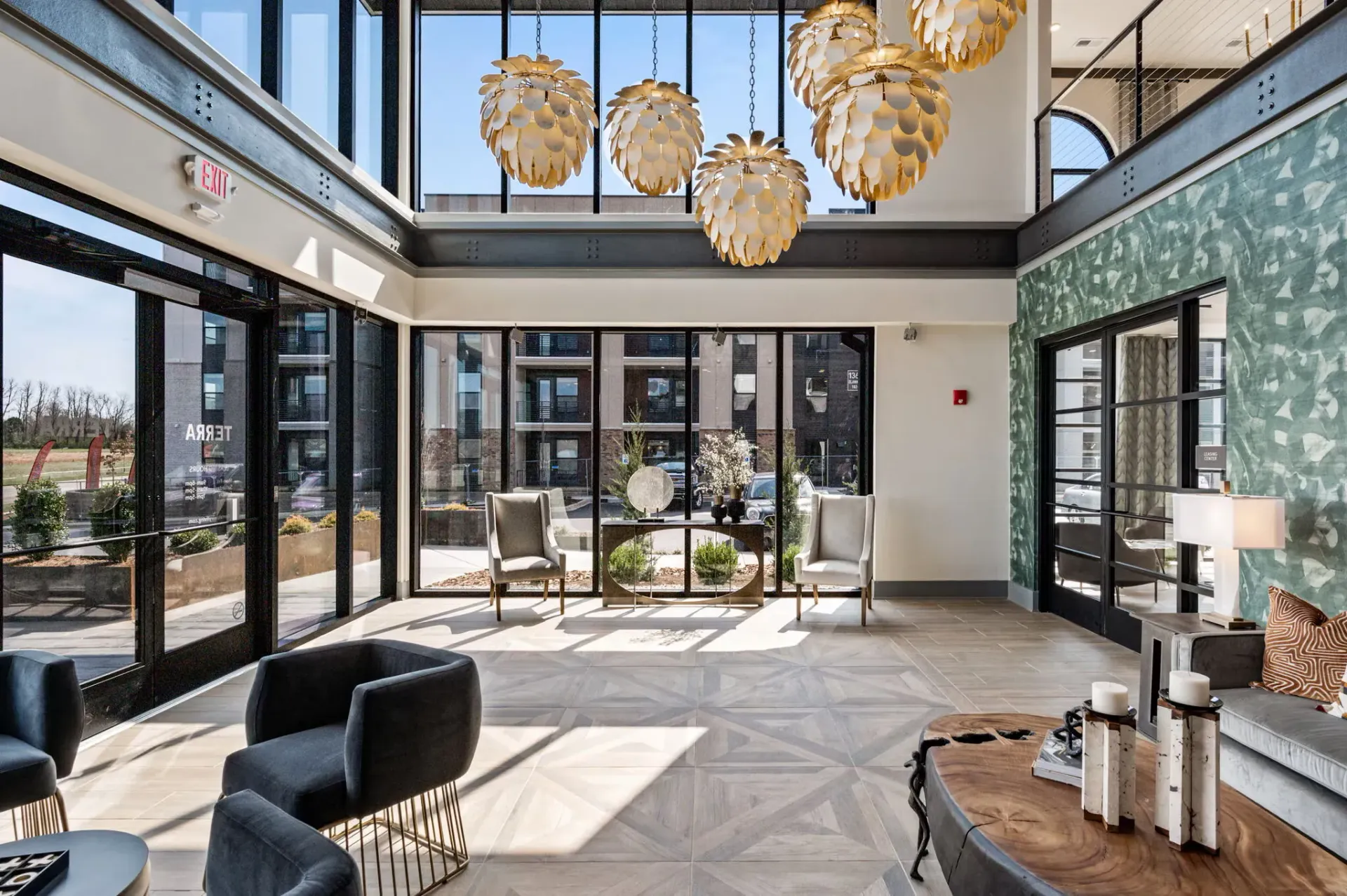 Bright modern apartment lobby with large windows, seating area, and oversized pendant lights.