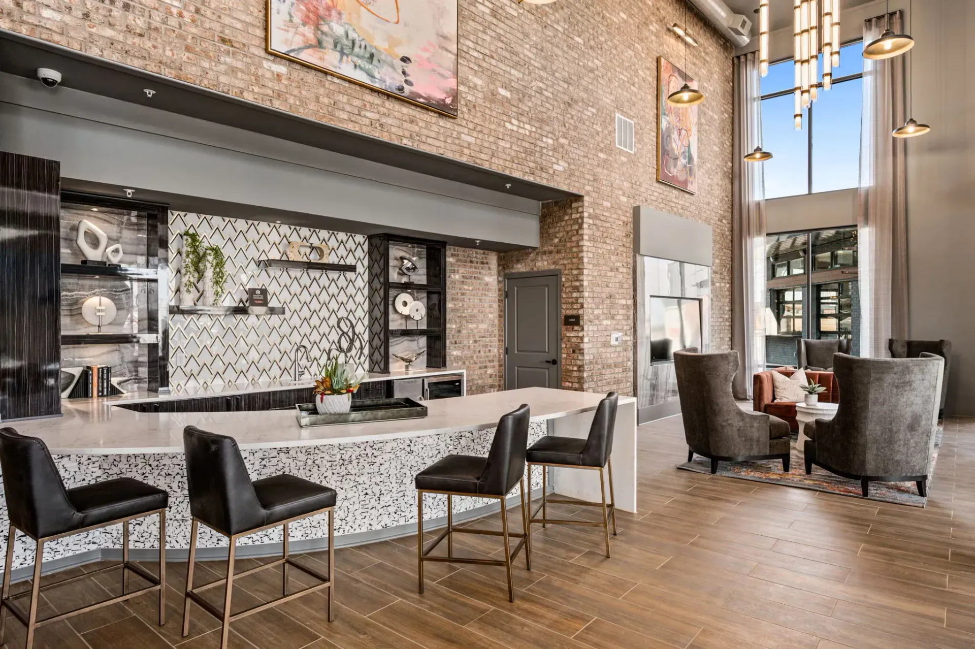 Interior community lounge with a marble bar, high stools, and brick walls.