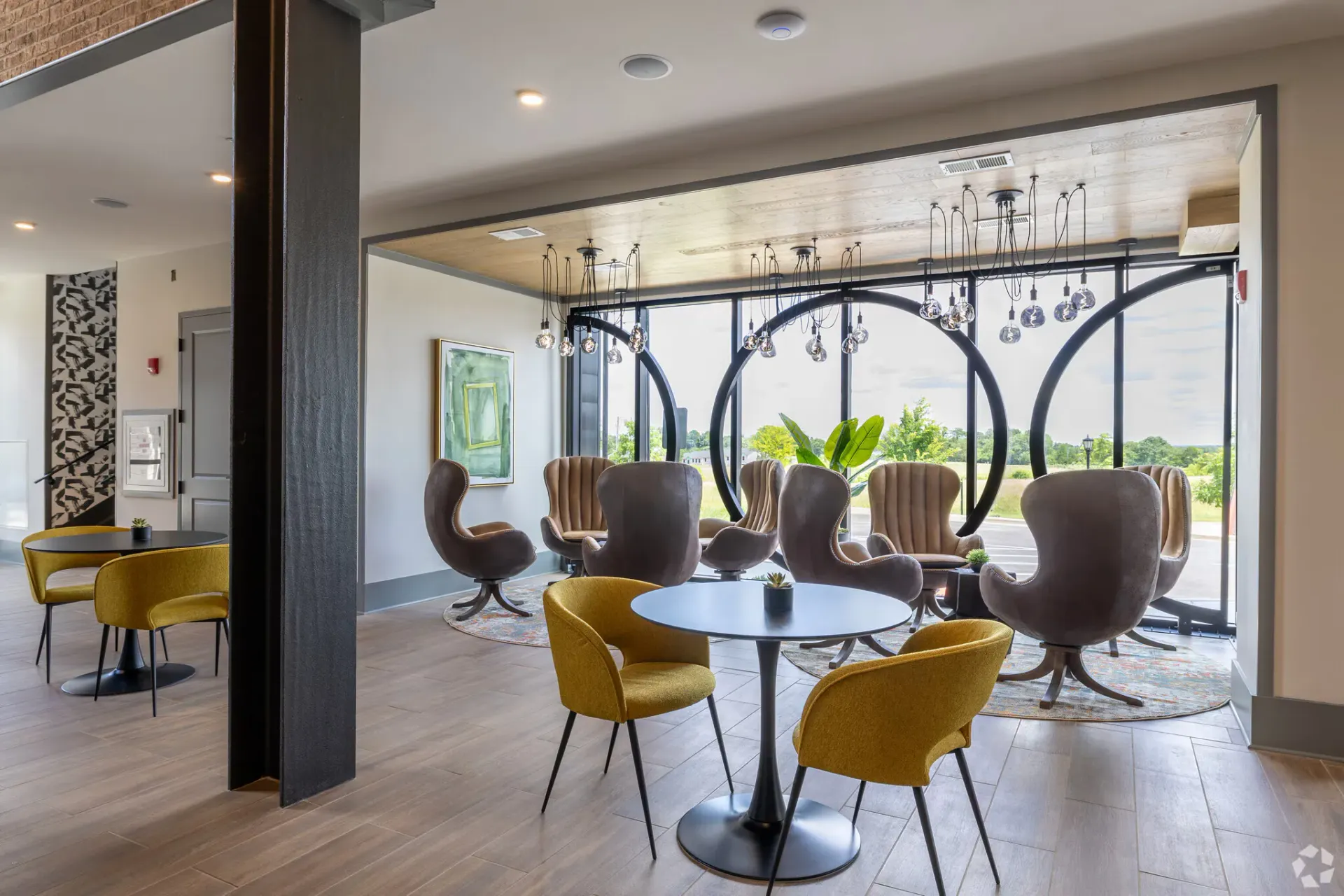 Contemporary residential lounge with yellow chairs, round window accents, and pendant lighting.