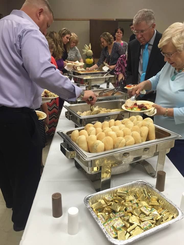 A group of people are standing around a buffet table.