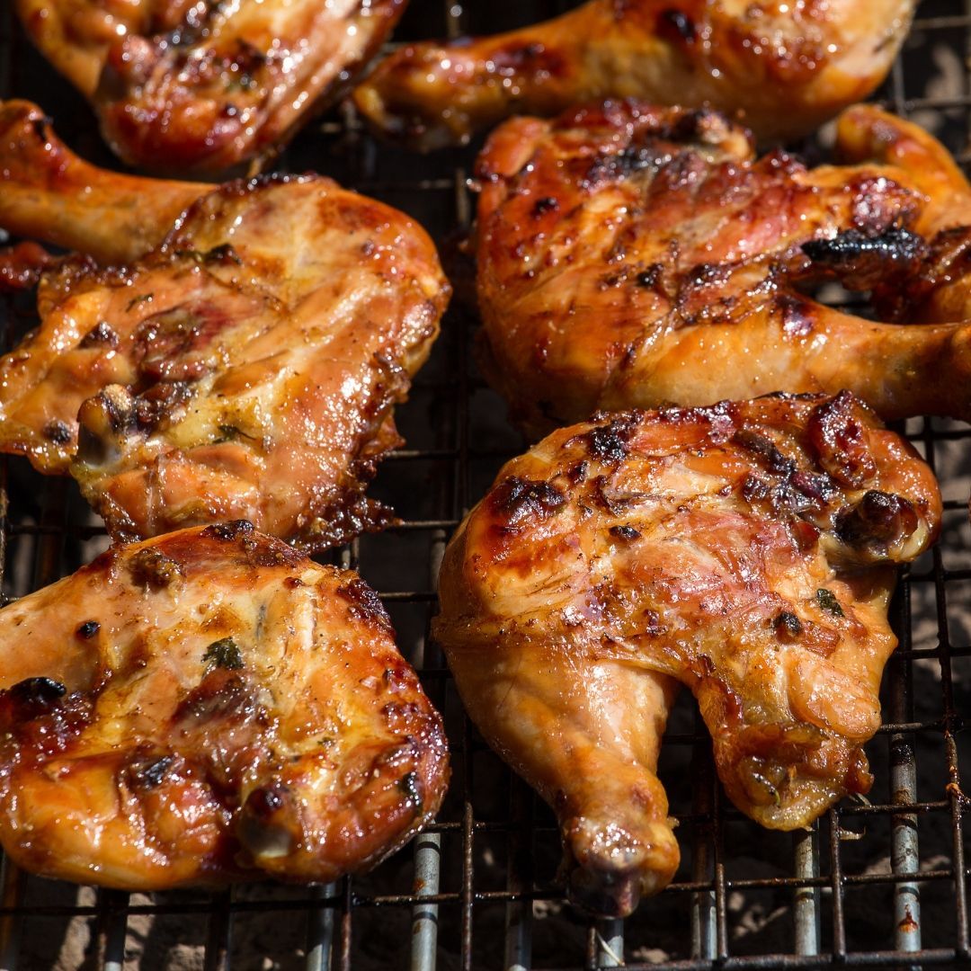 A bunch of chicken is cooking on a grill