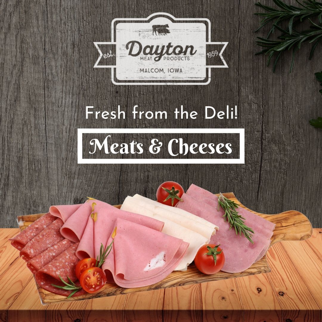 A wooden cutting board with meats and cheeses on it.