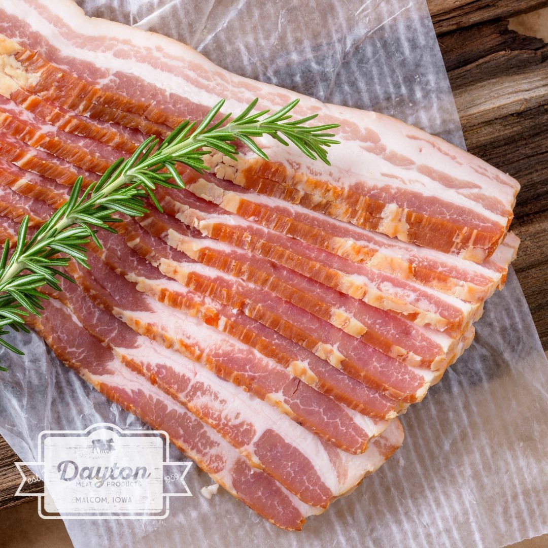 A piece of bacon is sitting on a piece of wax paper on a wooden table.