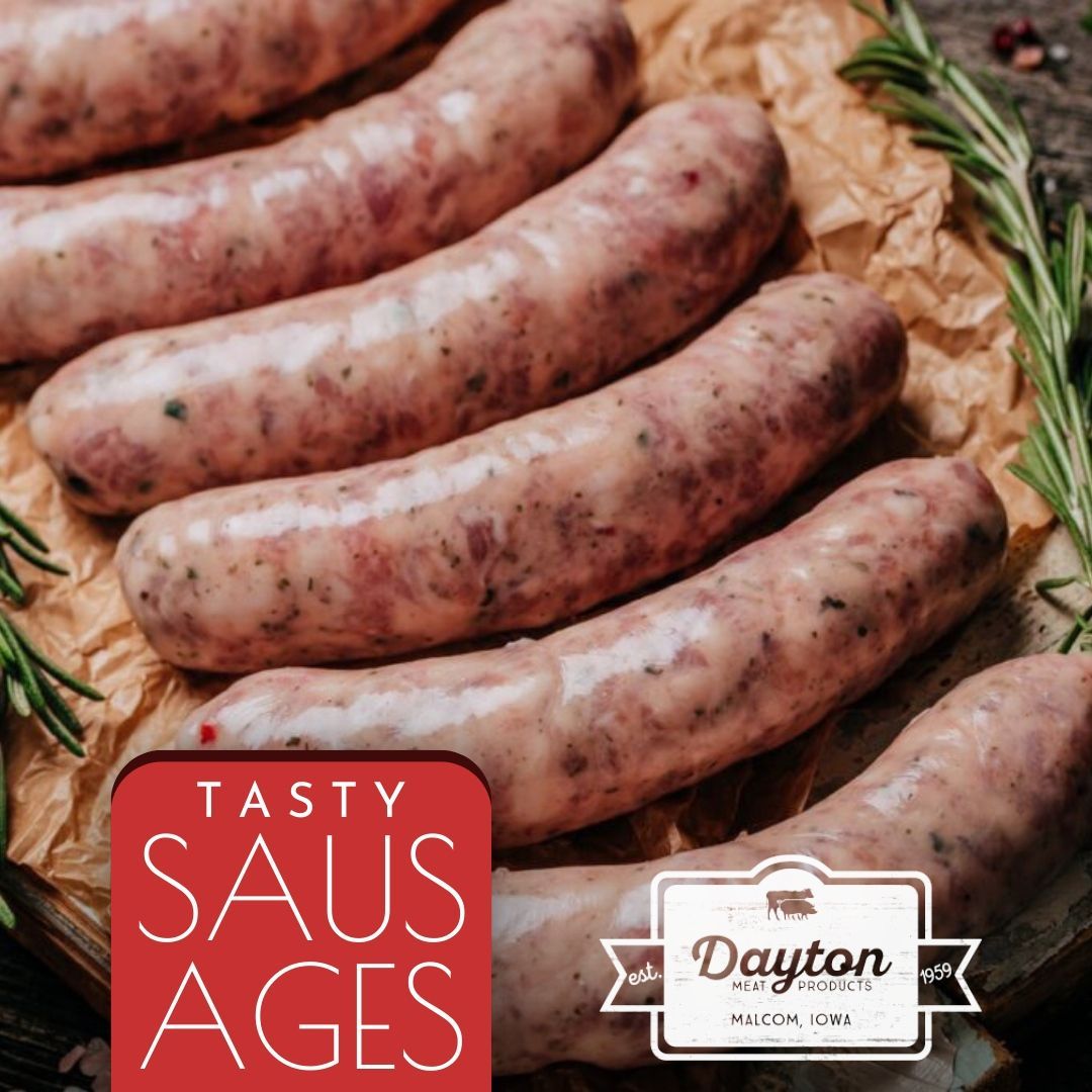 A bunch of sausages are sitting on a table with a sign that says tasty saus ages