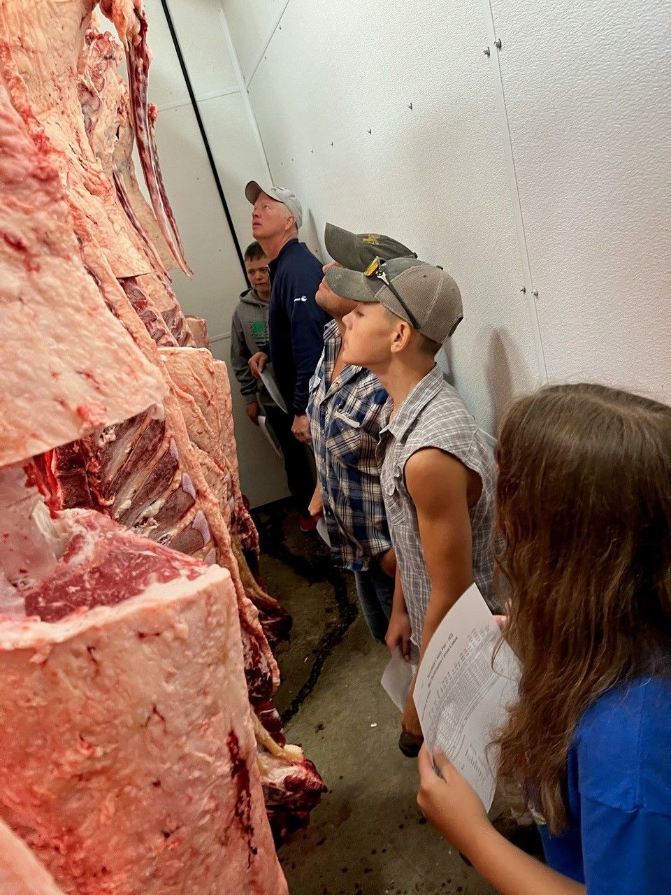 A group of people are looking at a large piece of meat.