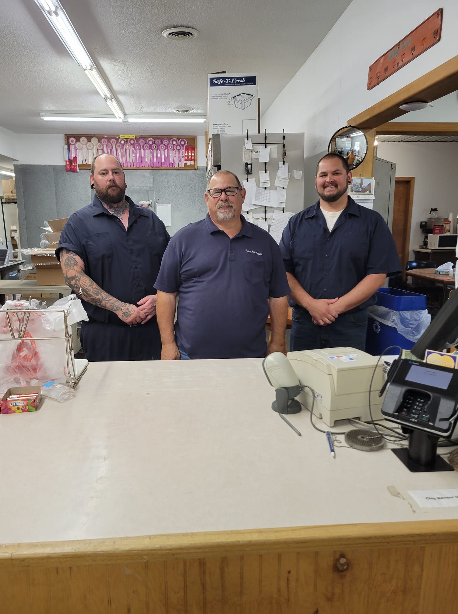Three men are standing in front of a counter in a store.