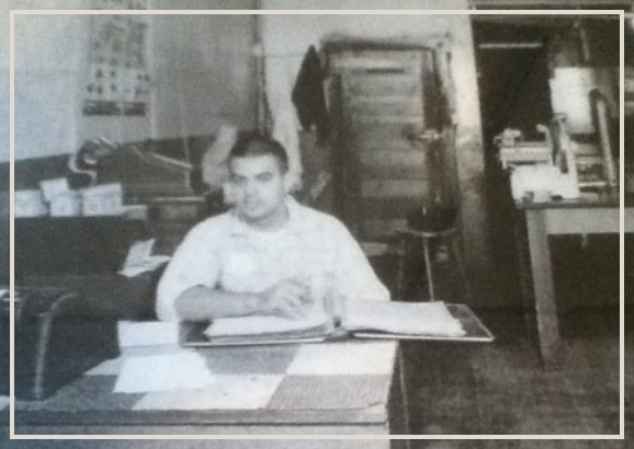 A black and white photo of a man sitting at a desk