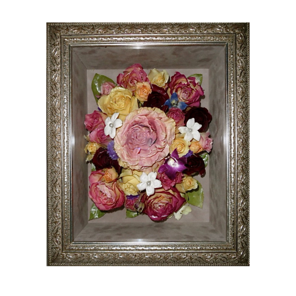 Framed bouquet of pressed flowers in pink, yellow, white, and purple on a gray background