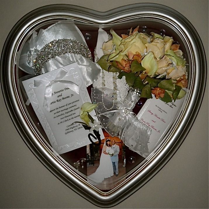 Heart-shaped silver keepsake frame with wedding mementos and a small couple photo inside