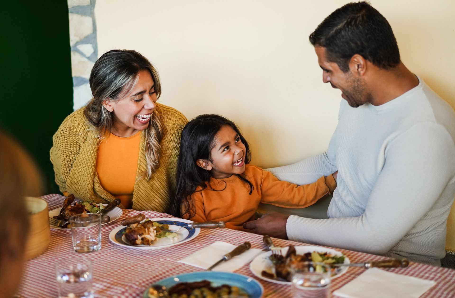 A family is sitting at a table with plates of food.