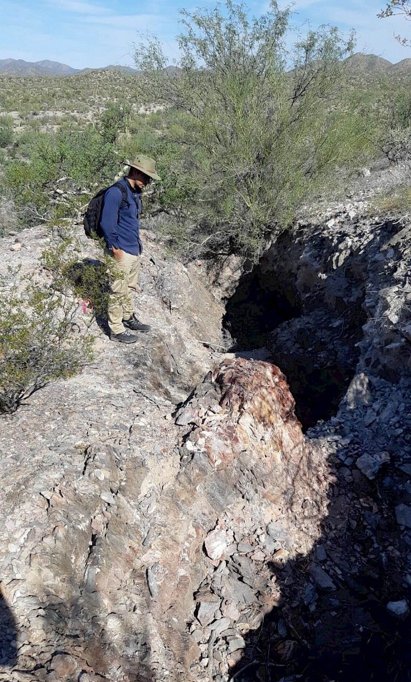 A man is standing on top of a rocky hill.
