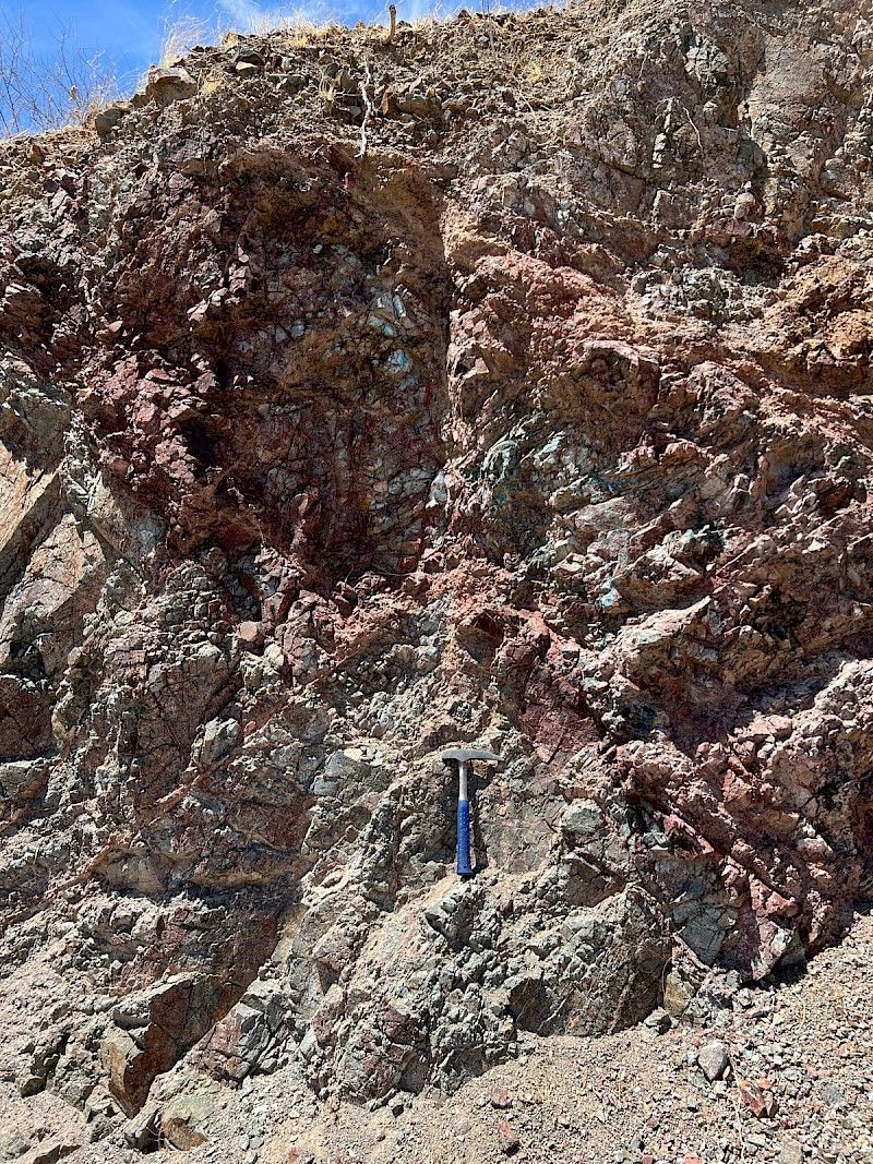 A person is standing in front of a large rock formation.