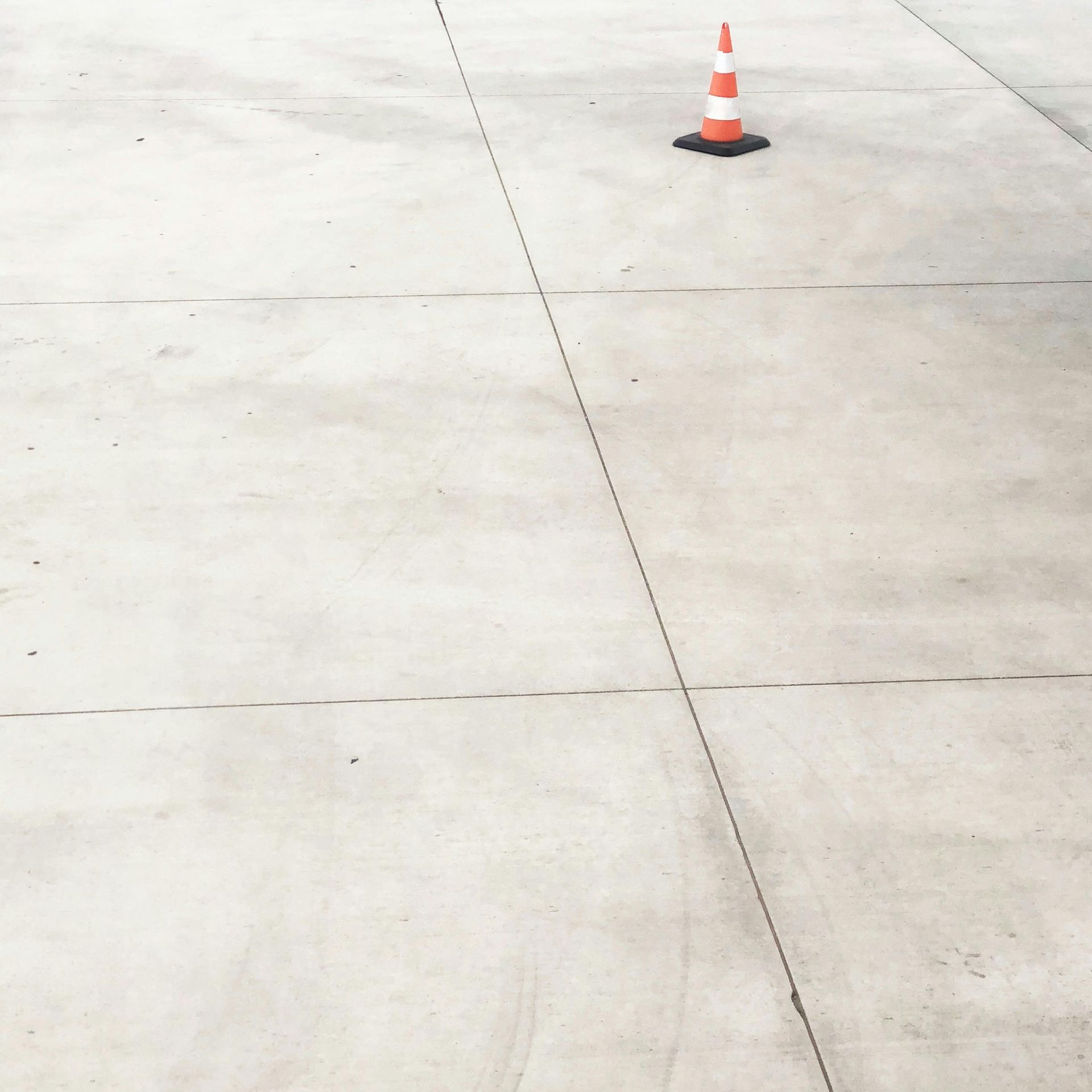 Concrete ground with orange and white traffic cone.