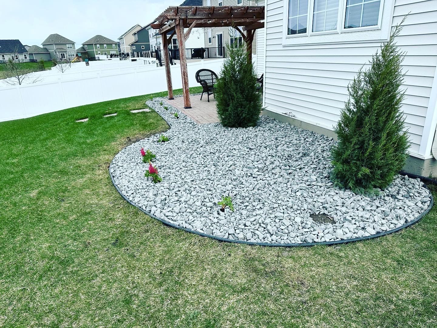 There is a gravel area in the backyard of a house.