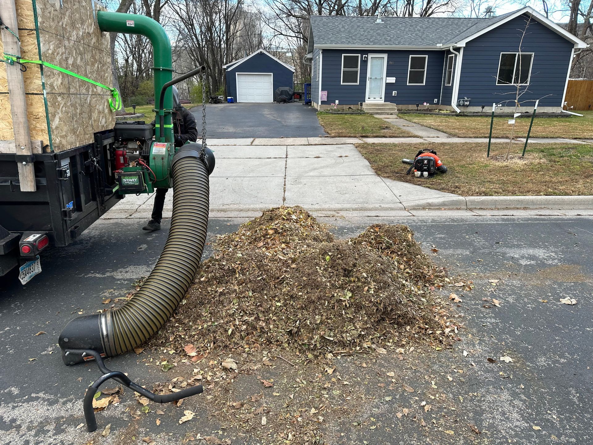 A leaf blower is being used to remove leaves from a driveway.