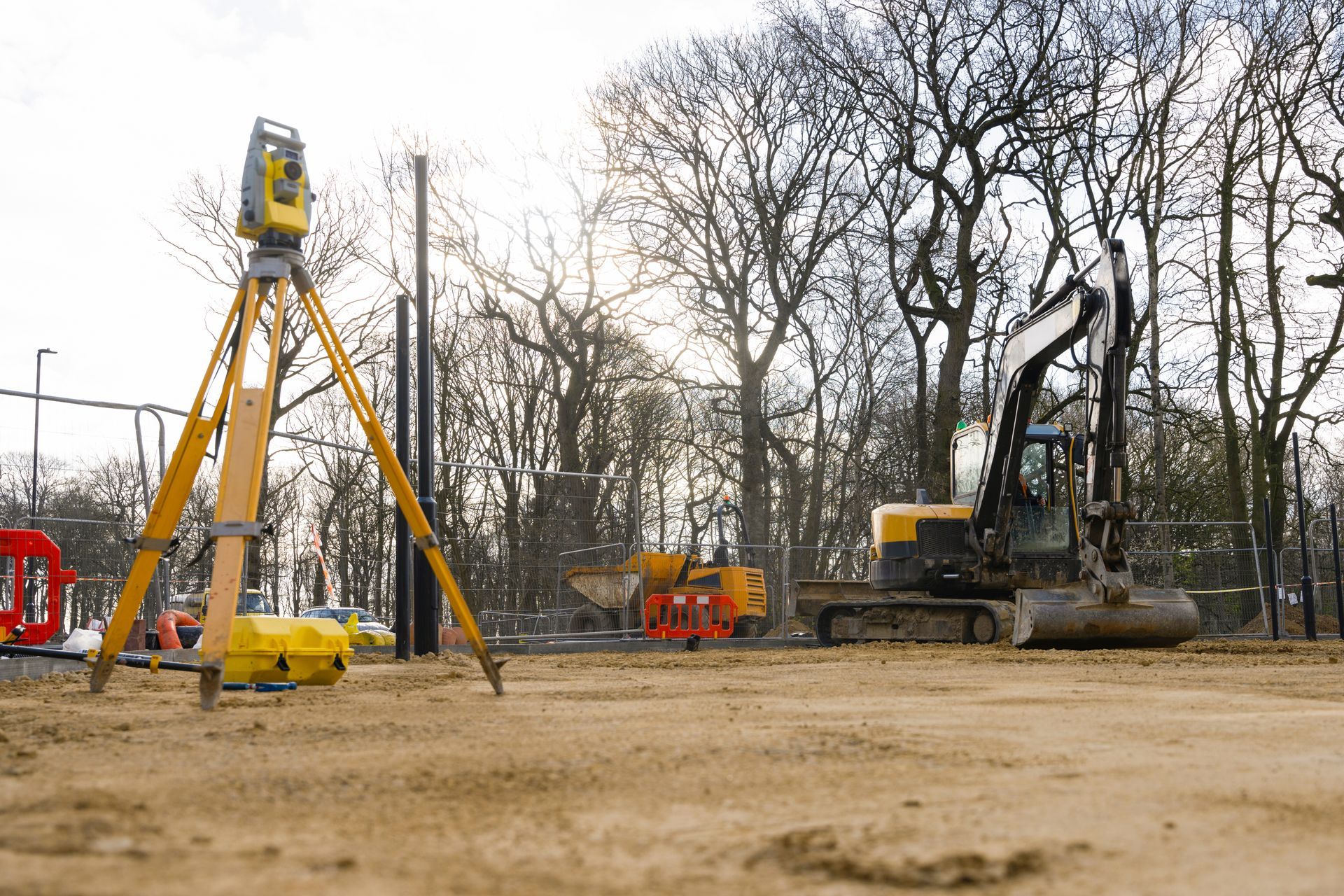 A construction site with a lot of machinery and trees in the background.