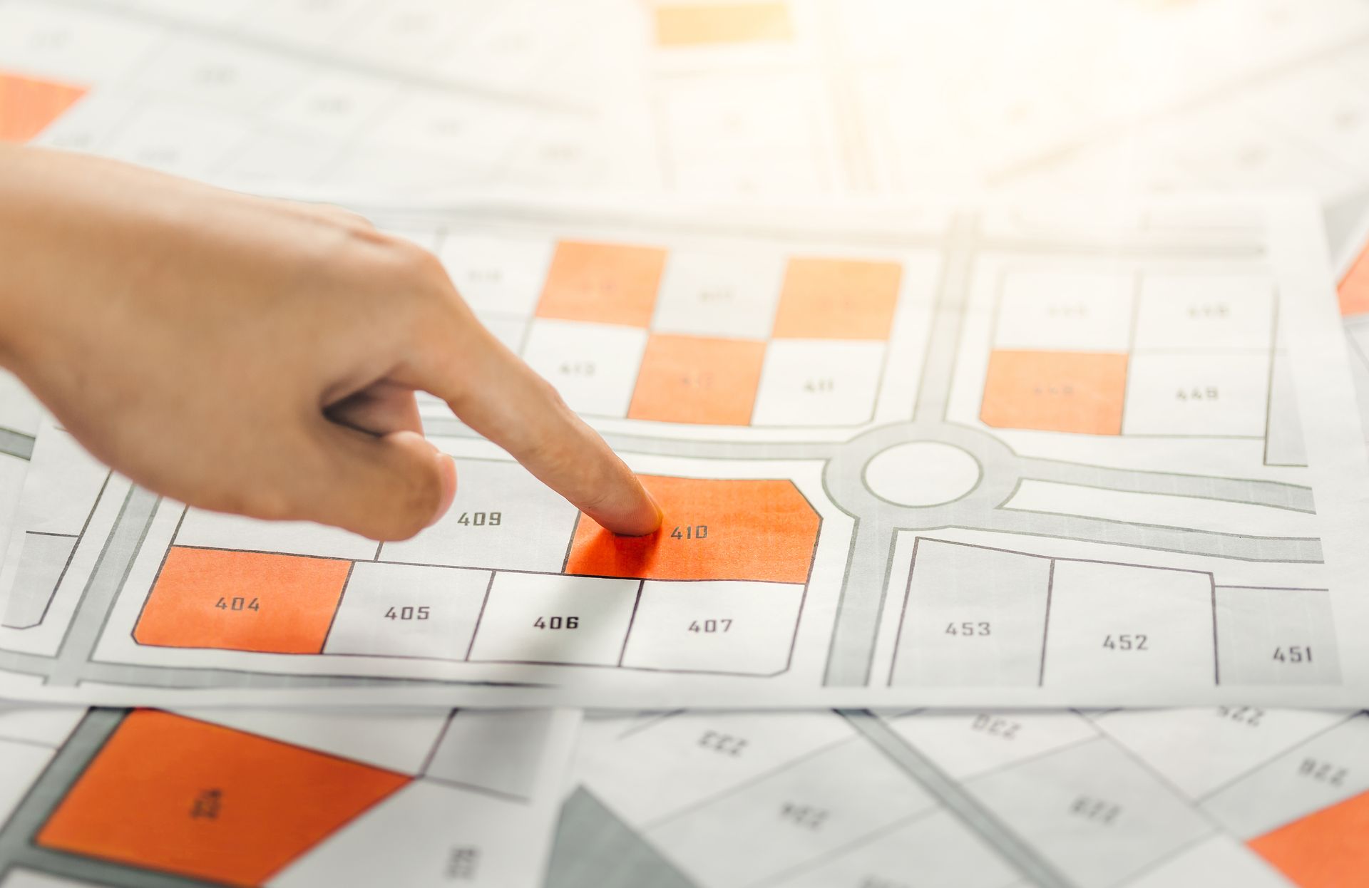 A person is pointing at a red square on a map.