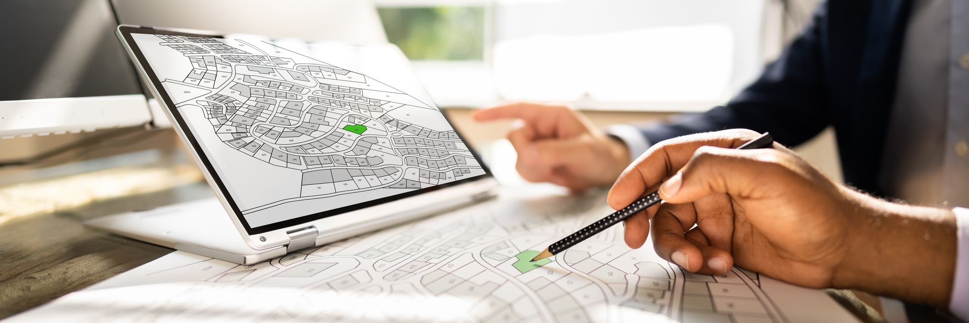 A person is pointing at a map on a laptop computer.