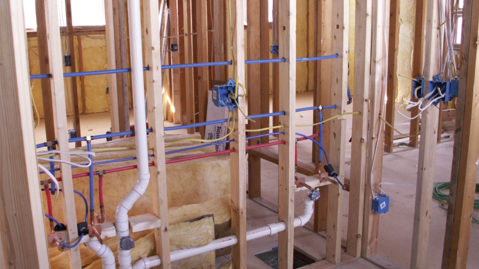 A house is being built with a lot of pipes and wires.