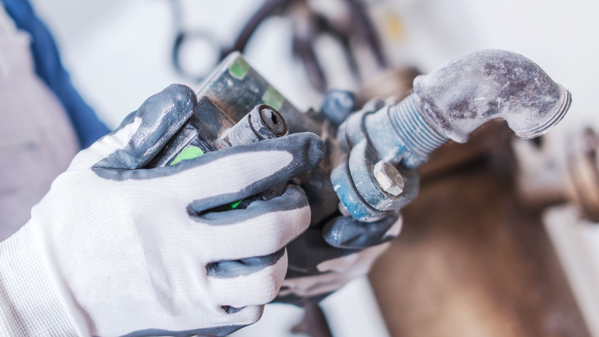 A person wearing gloves is holding a pipe in their hands.