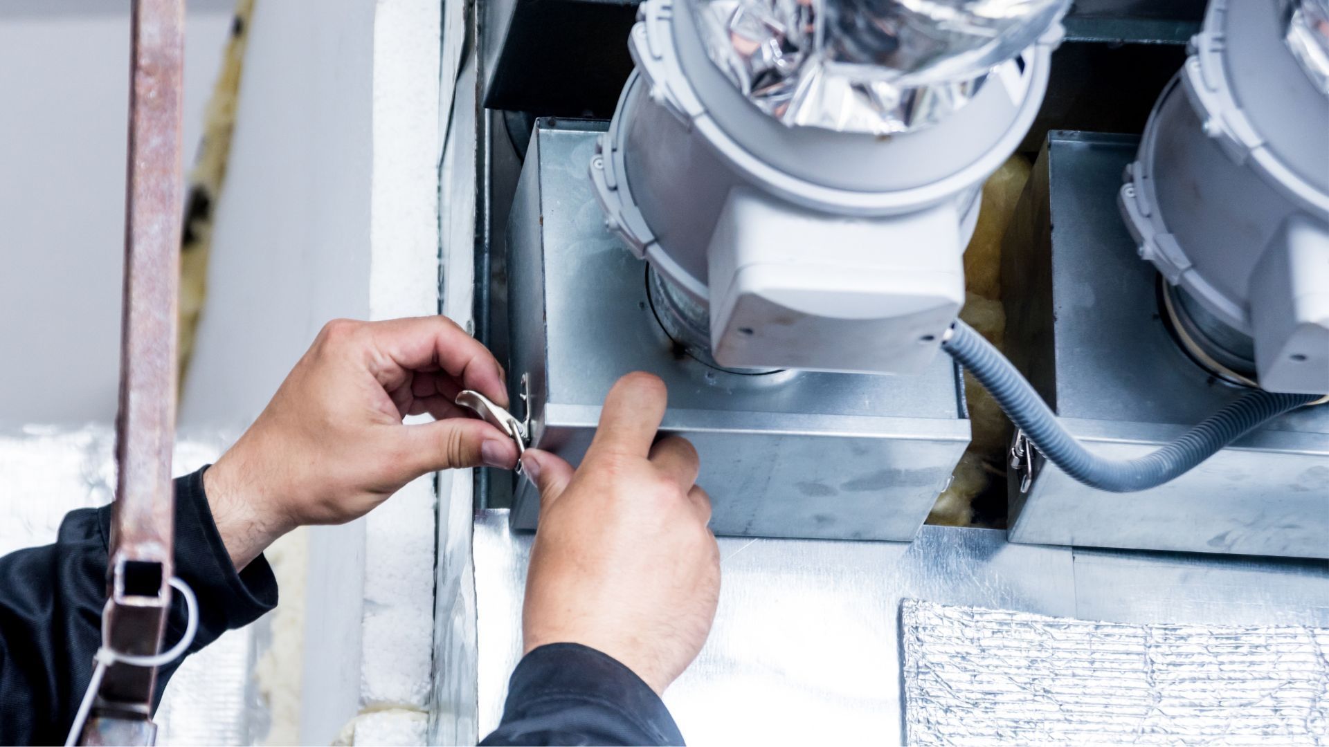 A man is working on a ventilation system in a building.