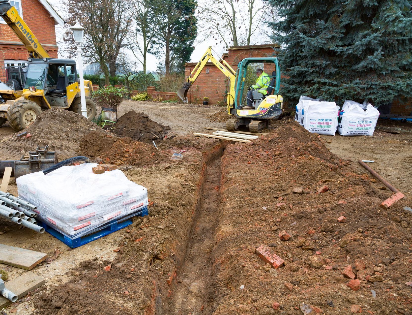 Un homme conduit une excavatrice jaune dans un champ de terre.