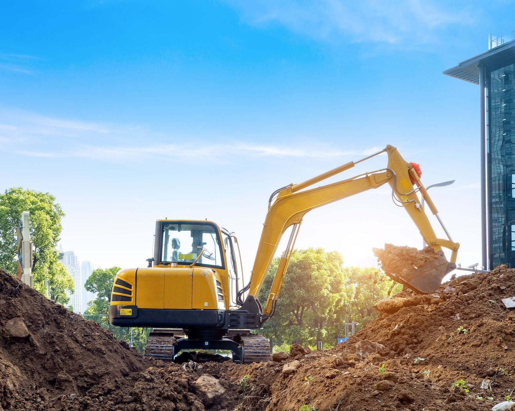 Une excavatrice jaune creuse un trou dans la terre sur un chantier de construction.