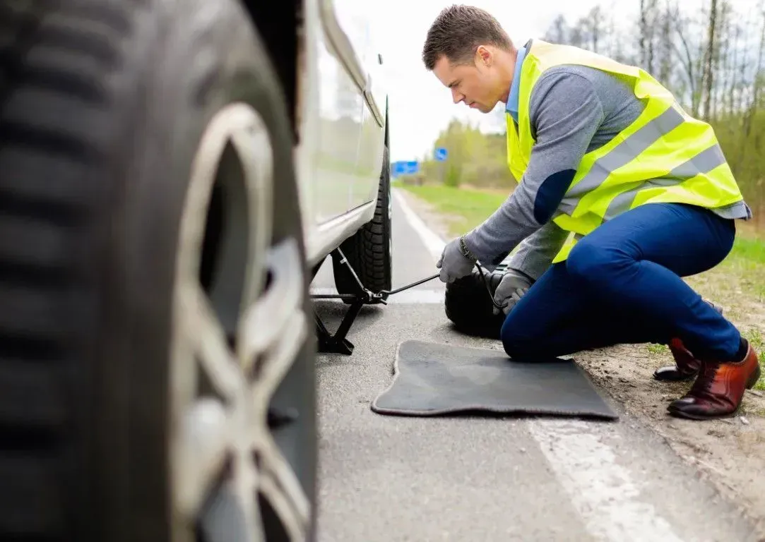 Roadside assistance worker changing a flat tire.