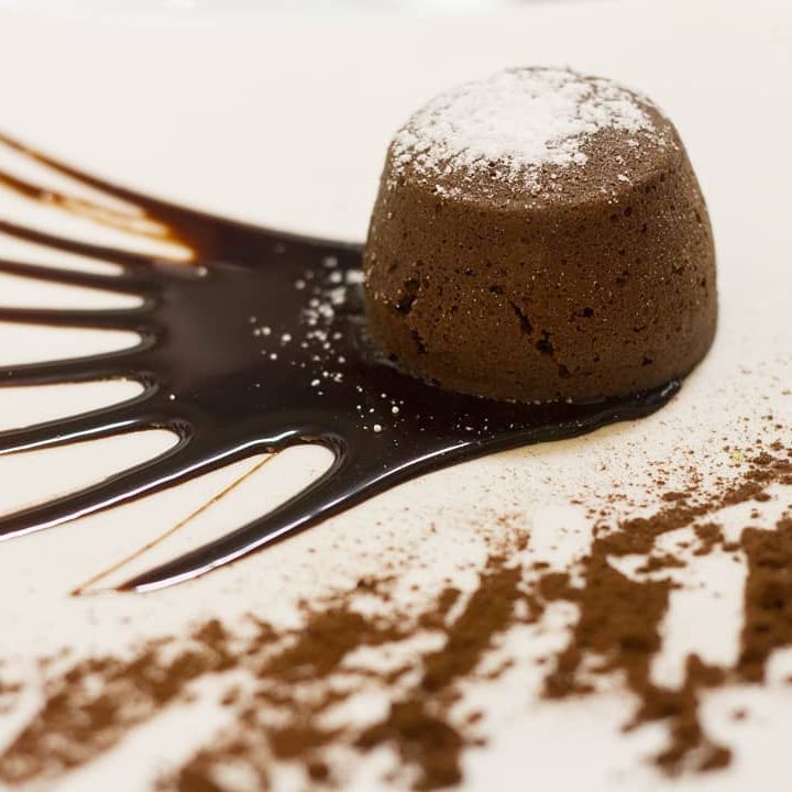 Su un piatto bianco c'è un dolce al cioccolato con zucchero a velo sopra