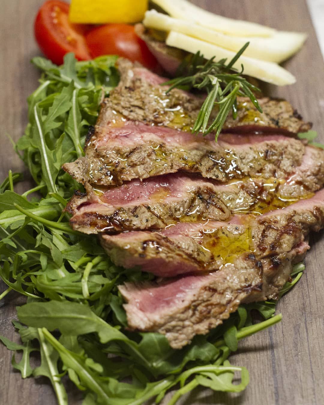 Un primo piano di un piatto di cibo con carne e verdure su un tavolo di legno.