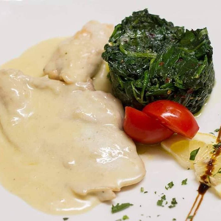 Un piatto di cibo con spinaci e pomodori sopra