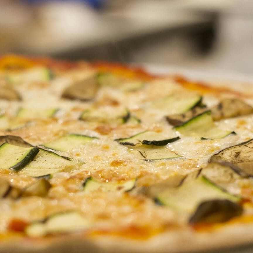 Un primo piano di una pizza con verdure su un tavolo.