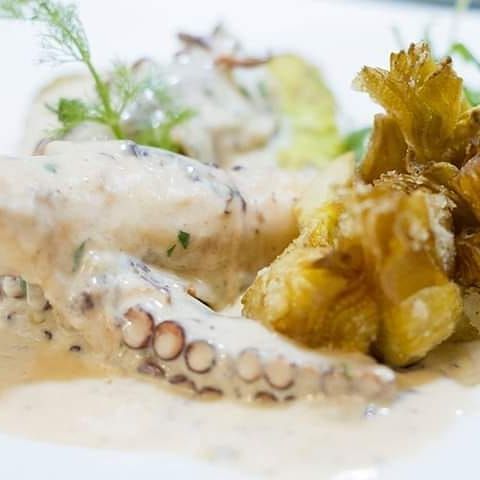 Un primo piano di un piatto di cibo con salsa e verdure su un tavolo.