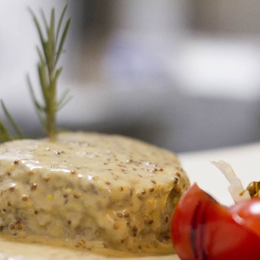 Un primo piano di un pezzo di cibo su un piatto con un pomodoro.