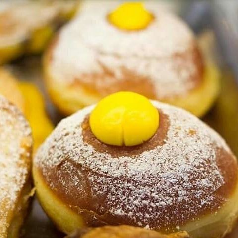 Un primo piano di una ciambella con zucchero a velo e una guarnizione gialla