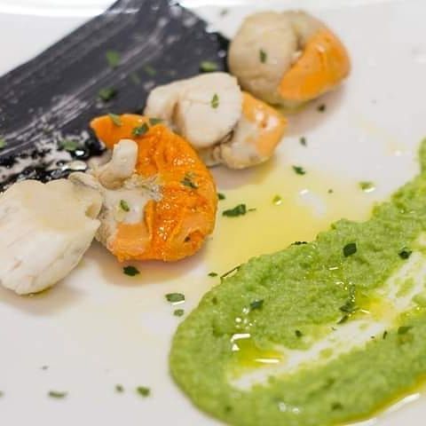 Un primo piano di un piatto di cibo con gamberetti e salsa verde su un tavolo.