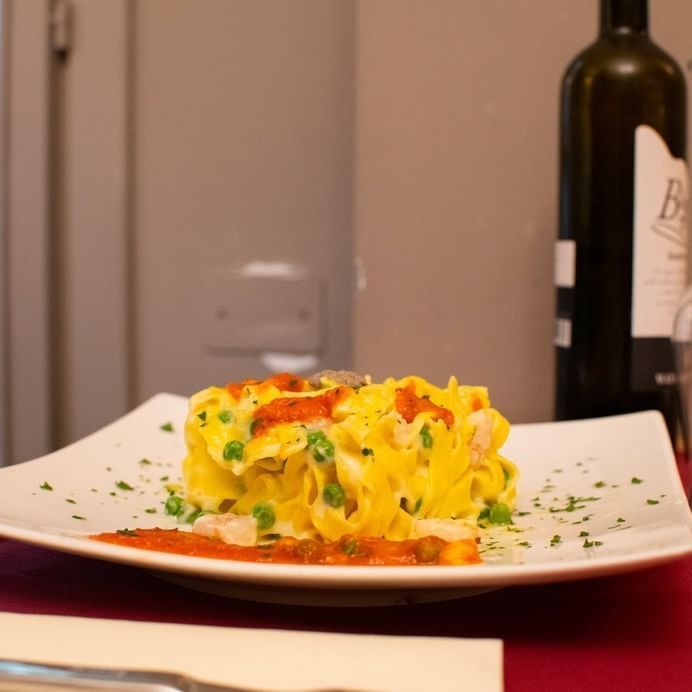 Un piatto di cibo con una bottiglia di vino in sottofondo