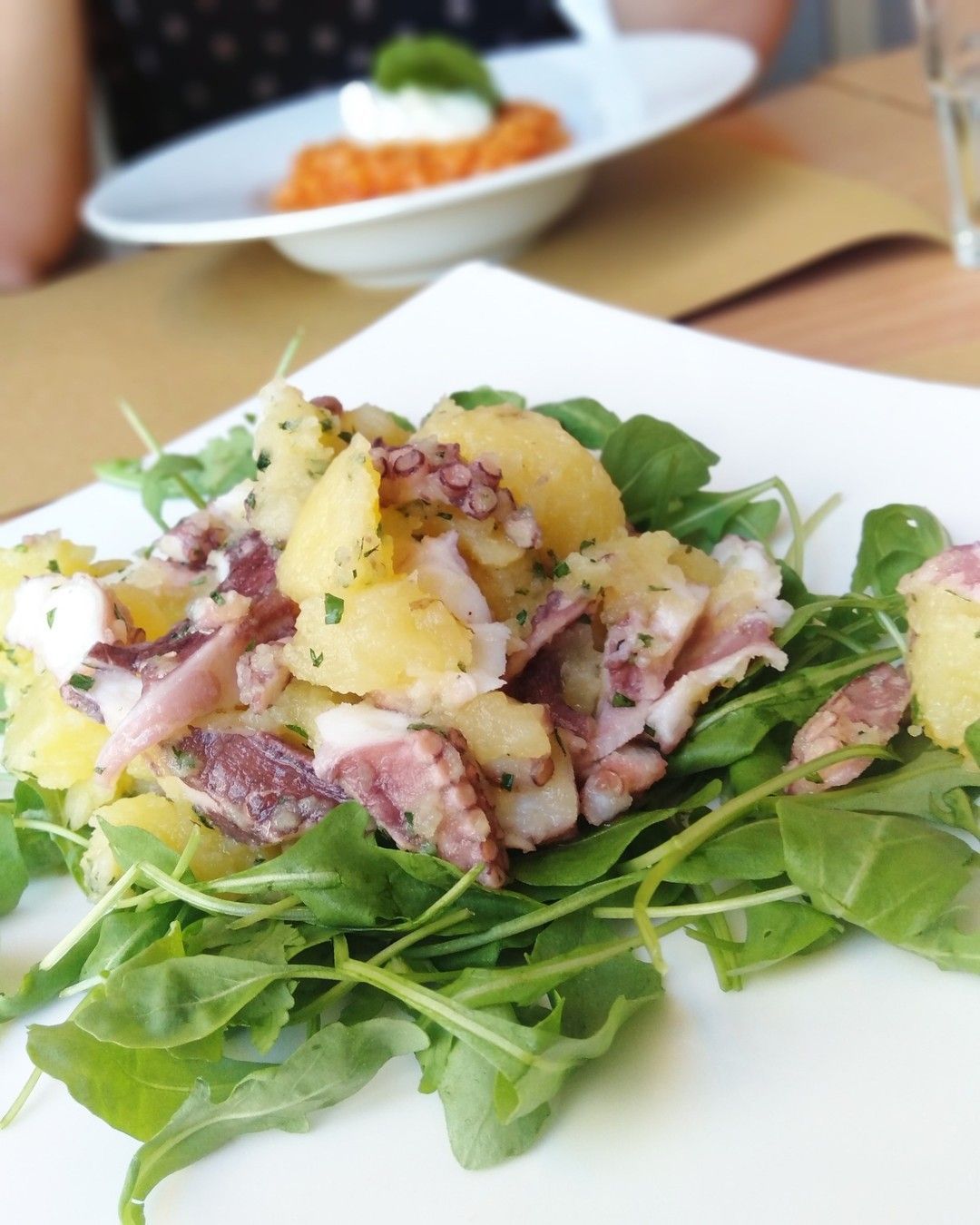 Un piatto di cibo con polpo e patate su un tavolo