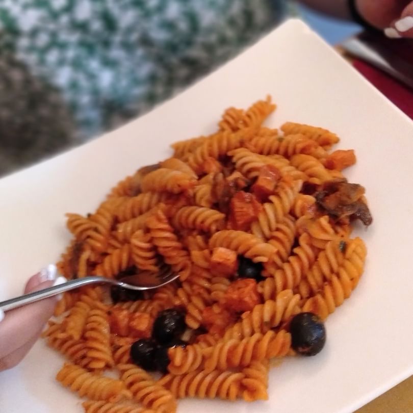 Una persona tiene una forchetta sopra un piatto di pasta