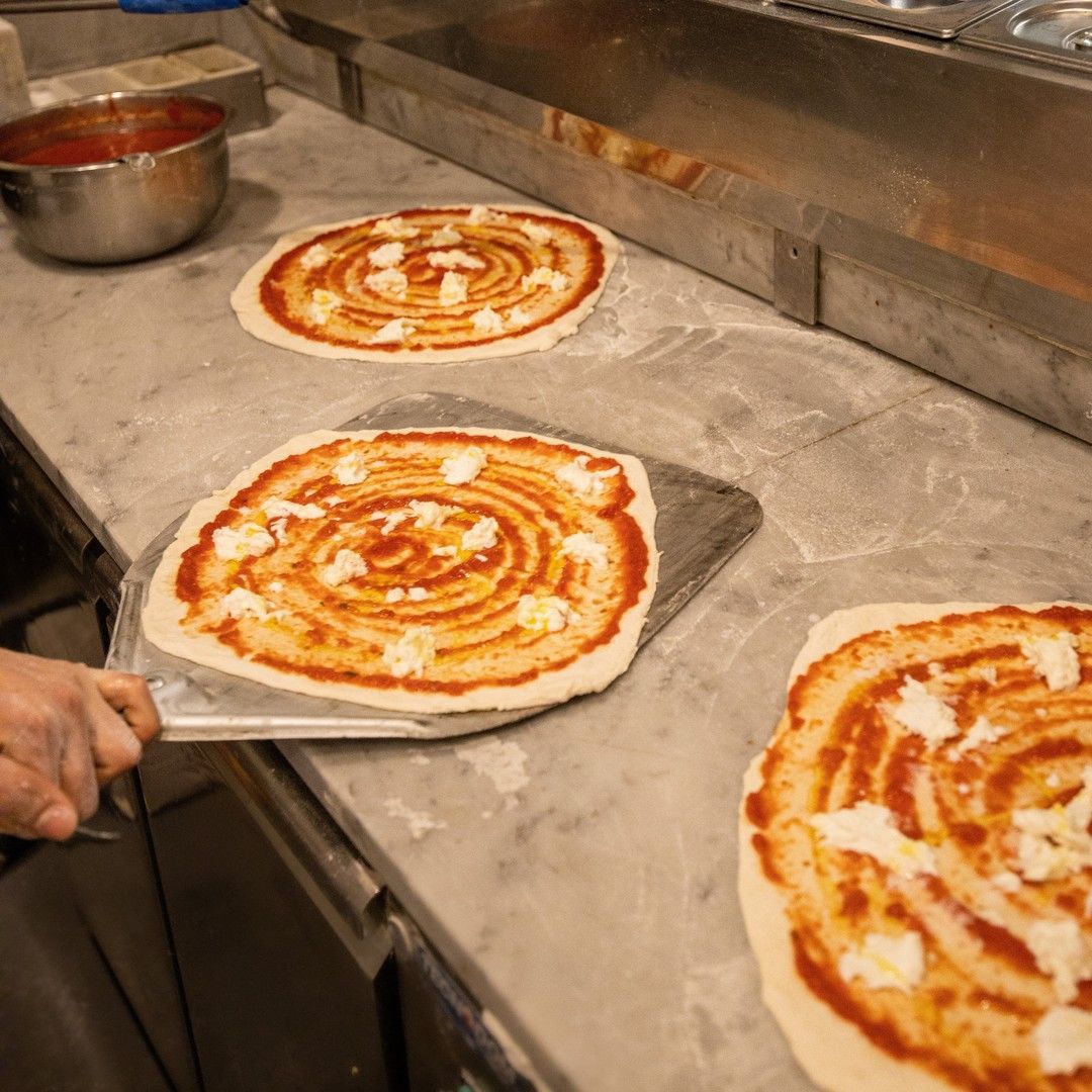 Una persona tiene una spatola sopra una pizza su un bancone.