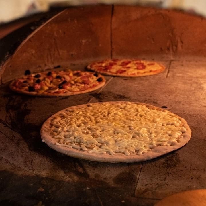 Tre pizze vengono cotte nel forno a legna