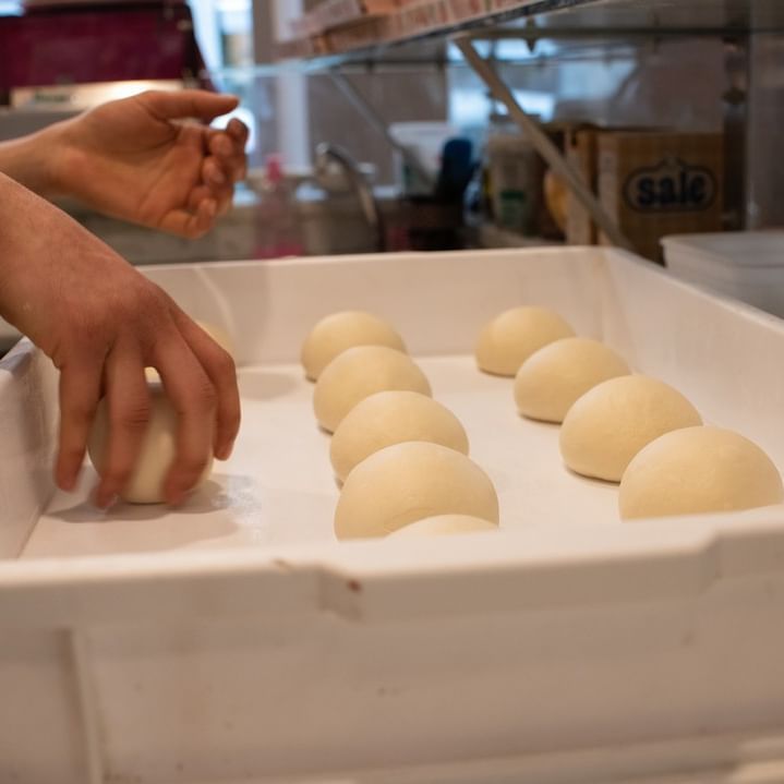 Una persona sta prendendo una pallina di pasta in una teglia