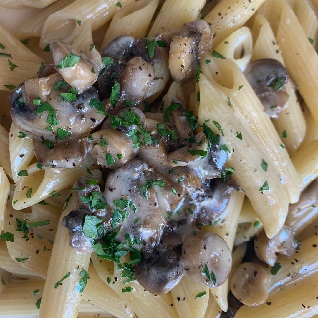 Un primo piano di un piatto di pasta con funghi e prezzemolo