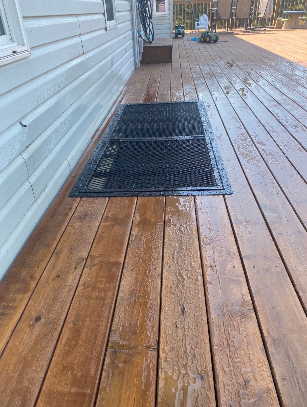 A wooden deck with a black mat on it next to a house.