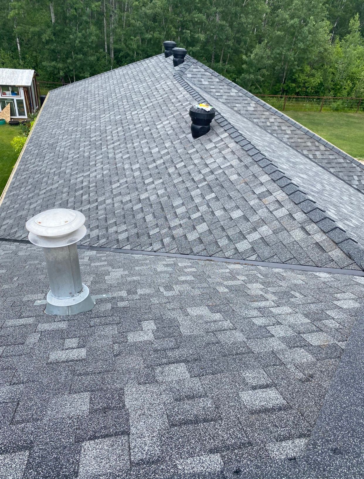 A roof with a chimney on it and trees in the background.