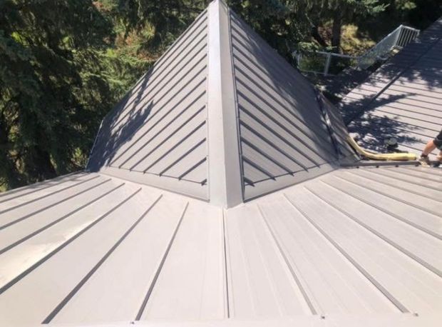 A man is standing on the roof of a house.