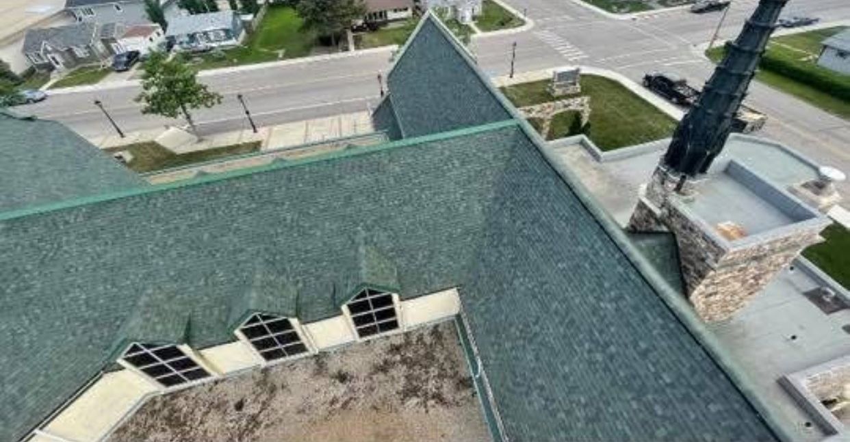 An aerial view of a church with a green roof and a chimney.