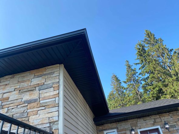 The roof of a house with a balcony and trees in the background.