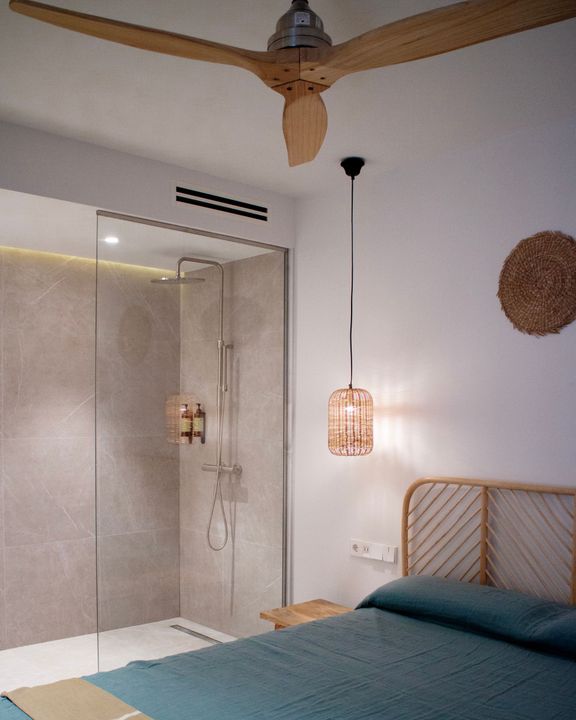 A bedroom with a ceiling fan and a walk in shower